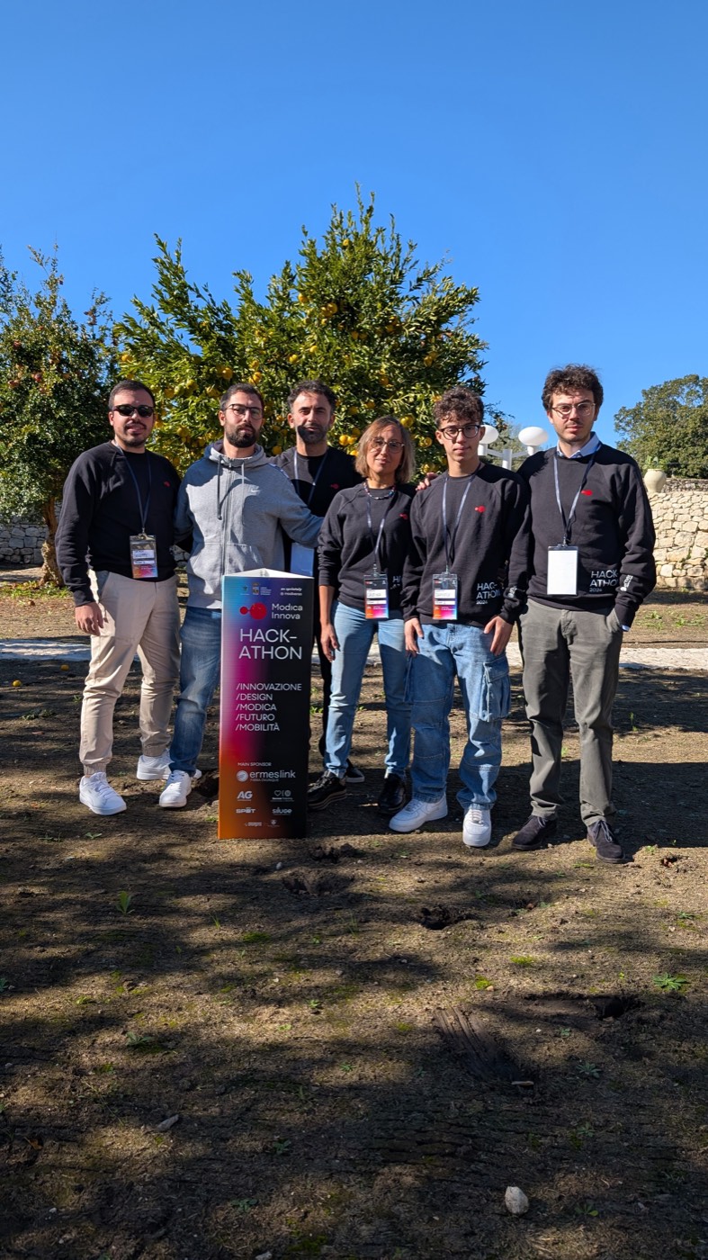 Un team posa all'aperto con il totem dell'hackathon